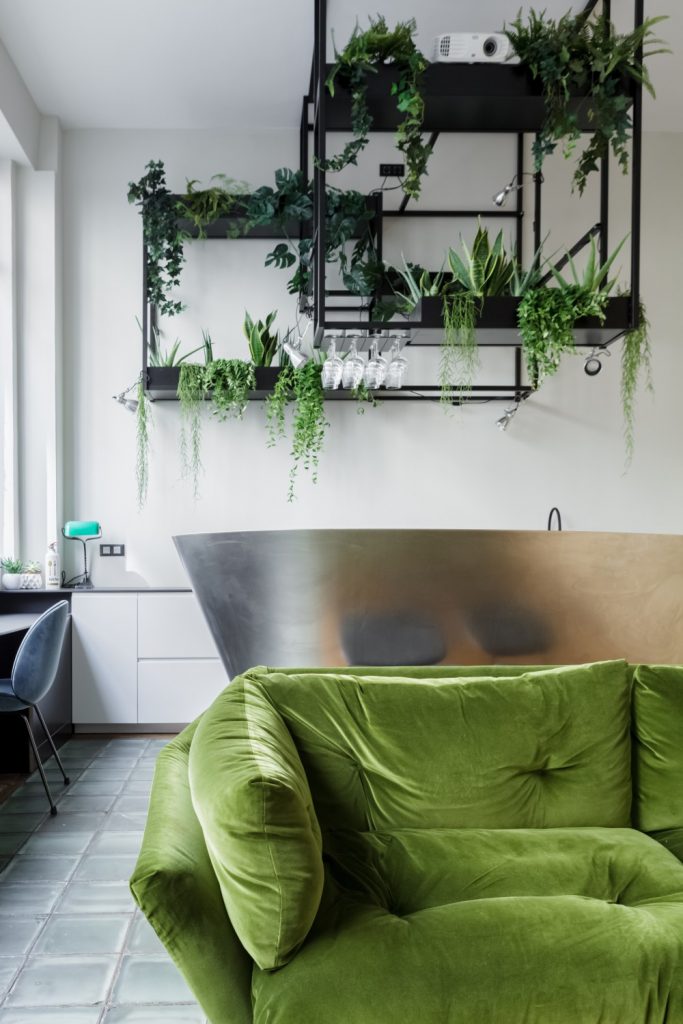 Un canapé en velours vert et de l'inox dans un appartement atypique à Paris