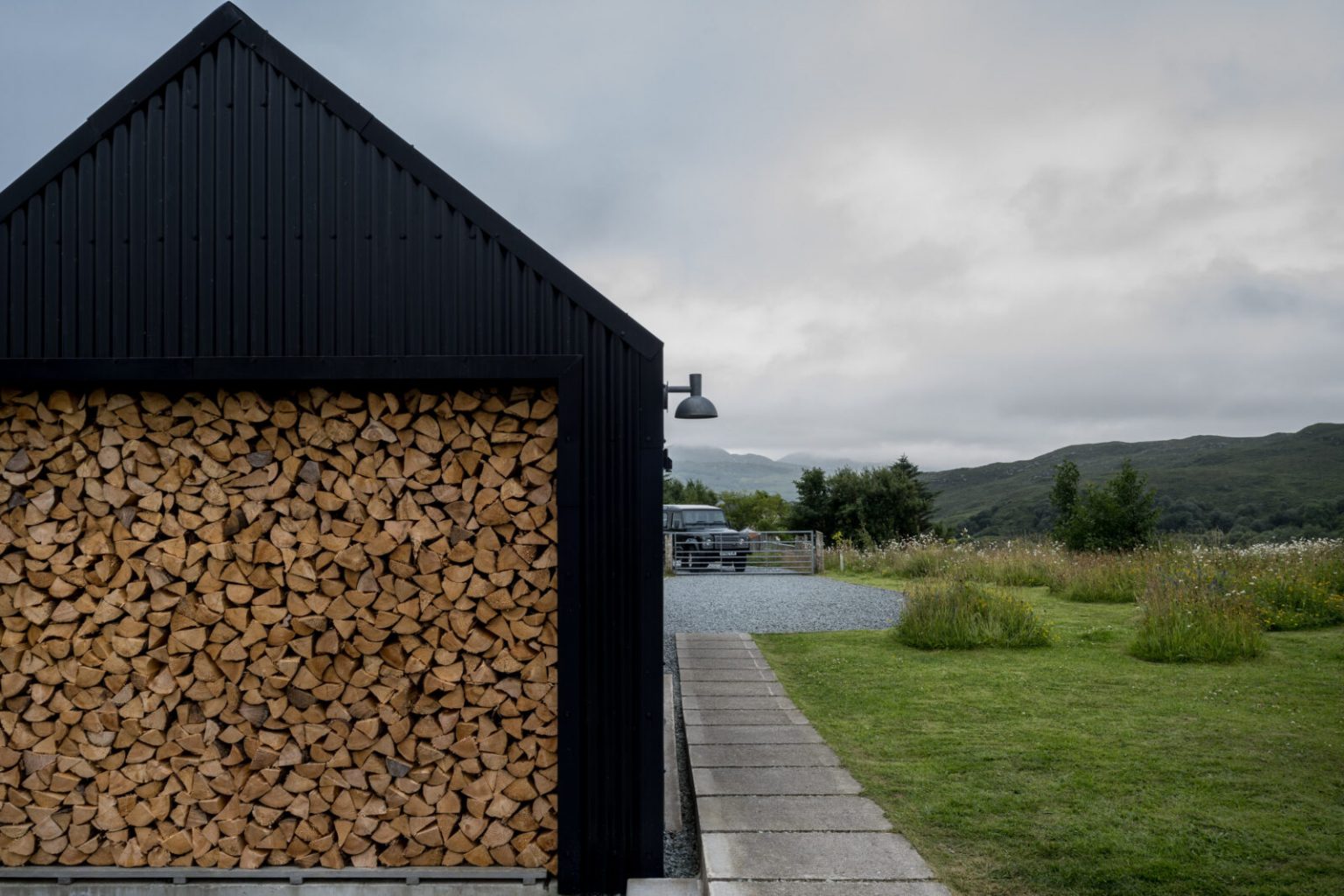 façade maison en aluminium noir avec réserve de bois
