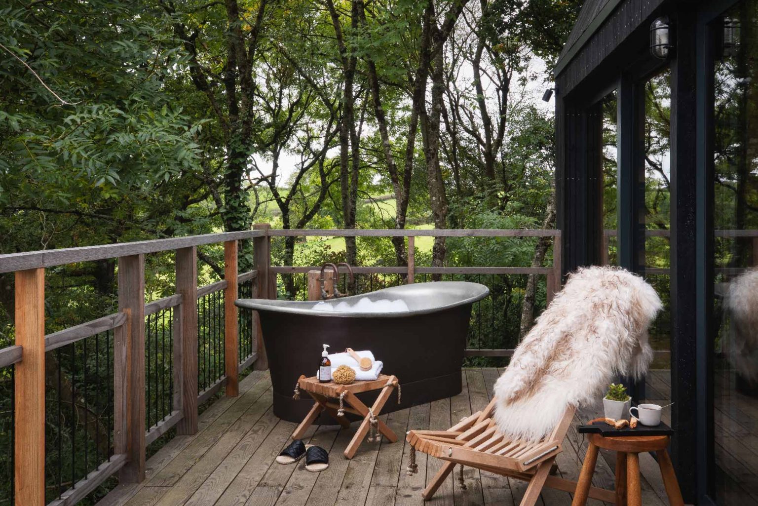 terrasse avec baignoire maison en bois noir dans les arbres