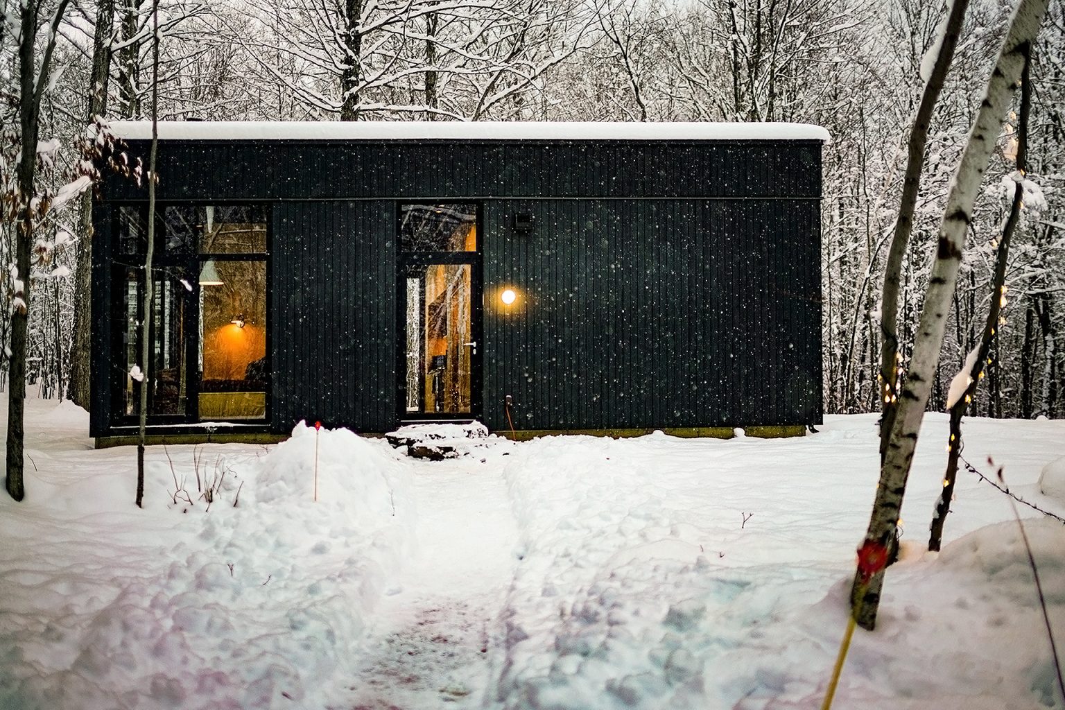 maison architecte design noire en verre dans la neige