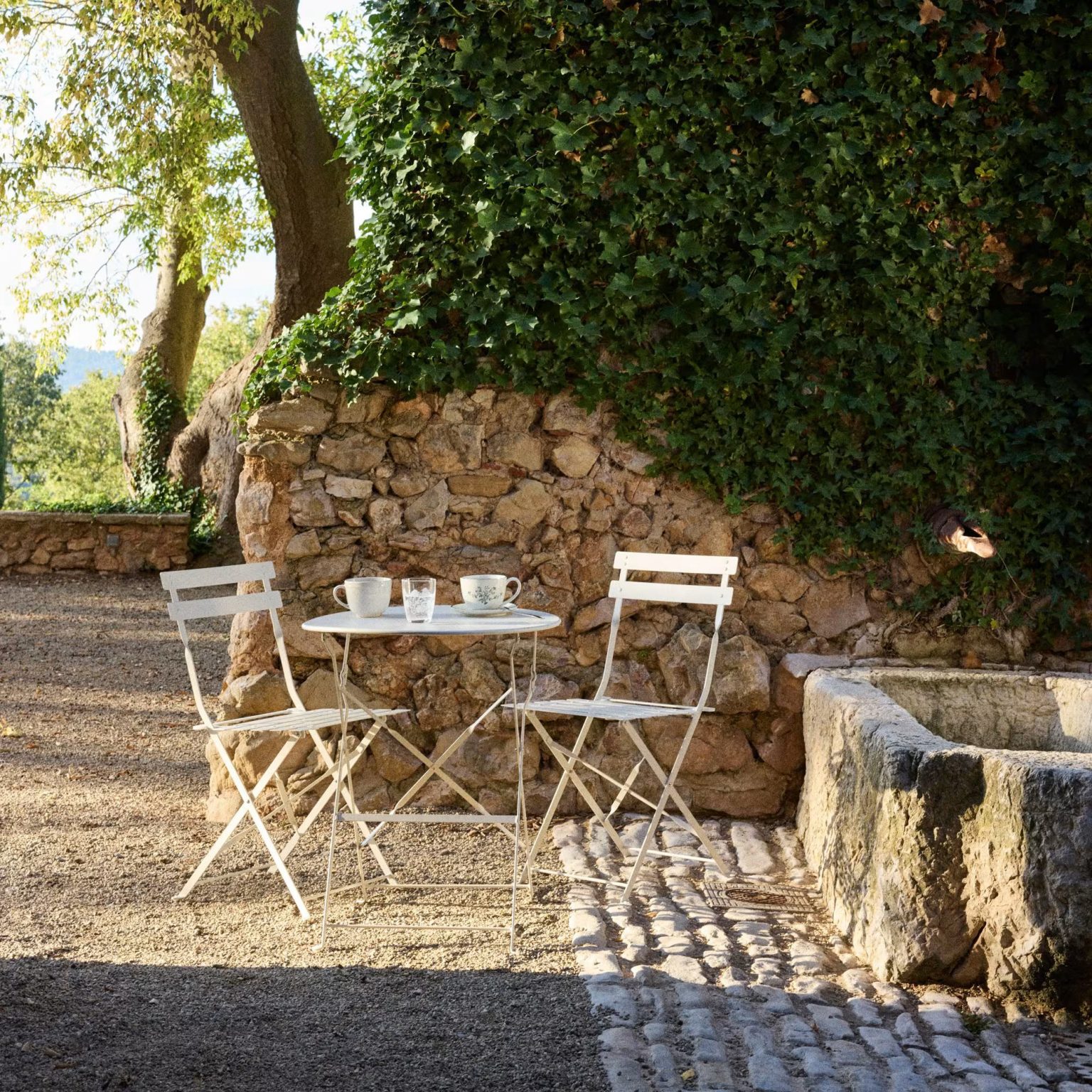salon de jardin Maisons du Monde collection French Riviera dans jardin avec mur de pierres