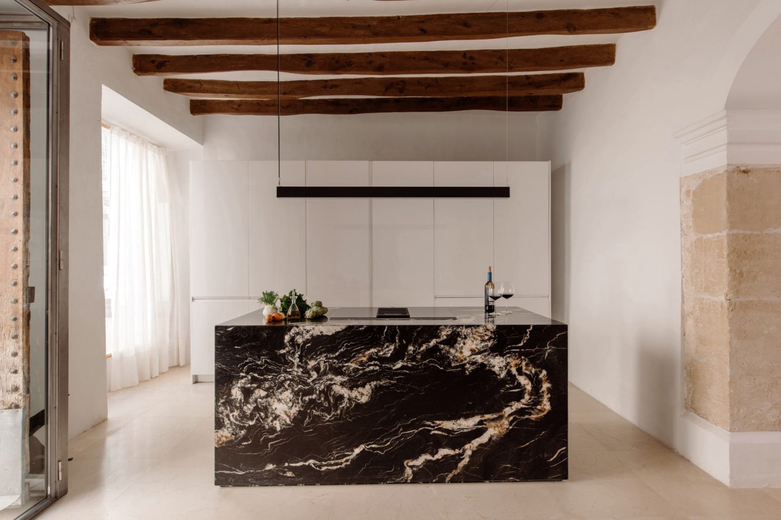 cuisine design blanche avec îlot marbre noir avec poutres décoration contemporaine maison ancienne Majorque