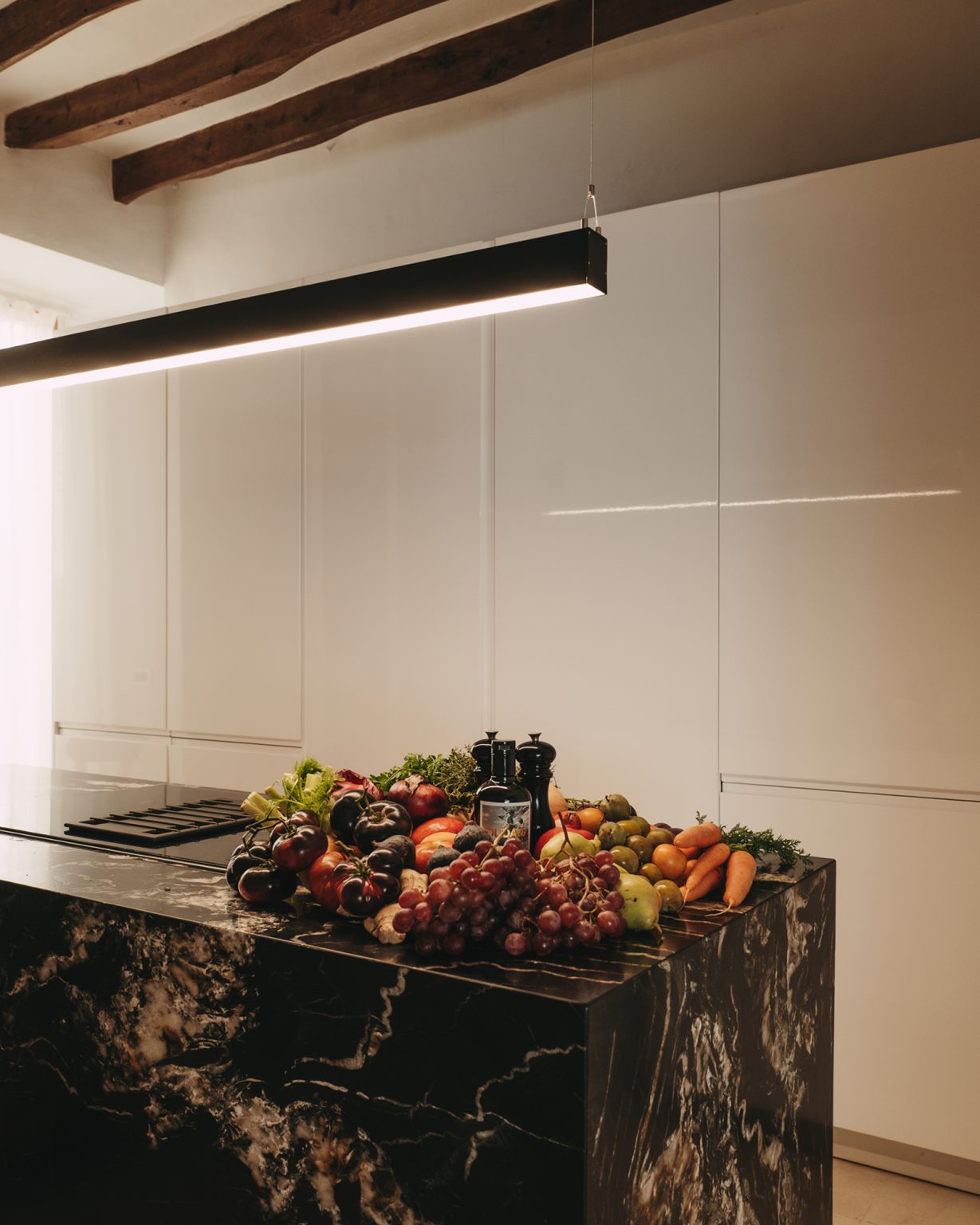 cuisine design blanche avec îlot marbre noir avec poutres décoration contemporaine maison ancienne Majorque