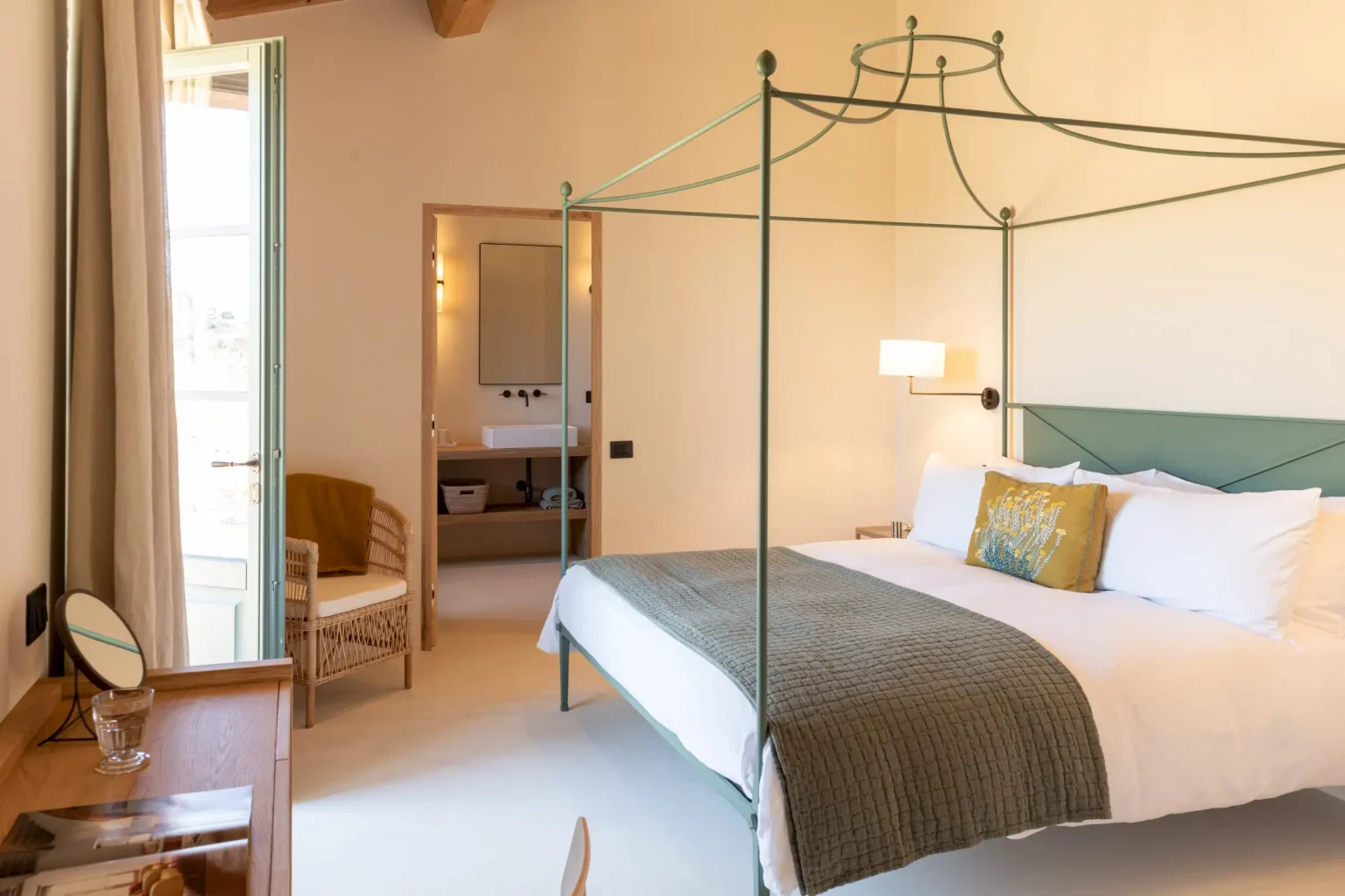 chambre avec lit baldaquin métal vert et poutres maison en pierres ancienne rénovée Podere Sirolo Italie