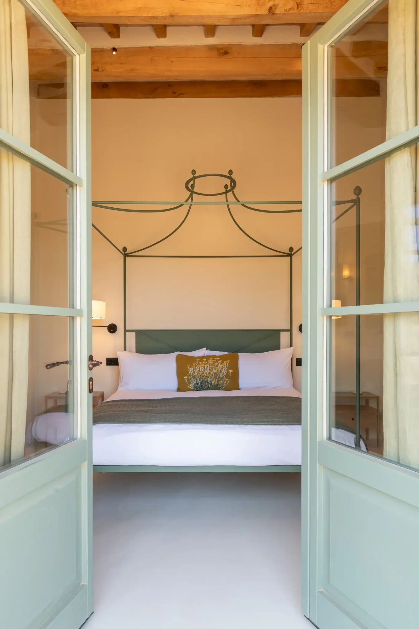 chambre avec lit baldaquin métal vert et poutres maison en pierres ancienne rénovée Podere Sirolo Italie