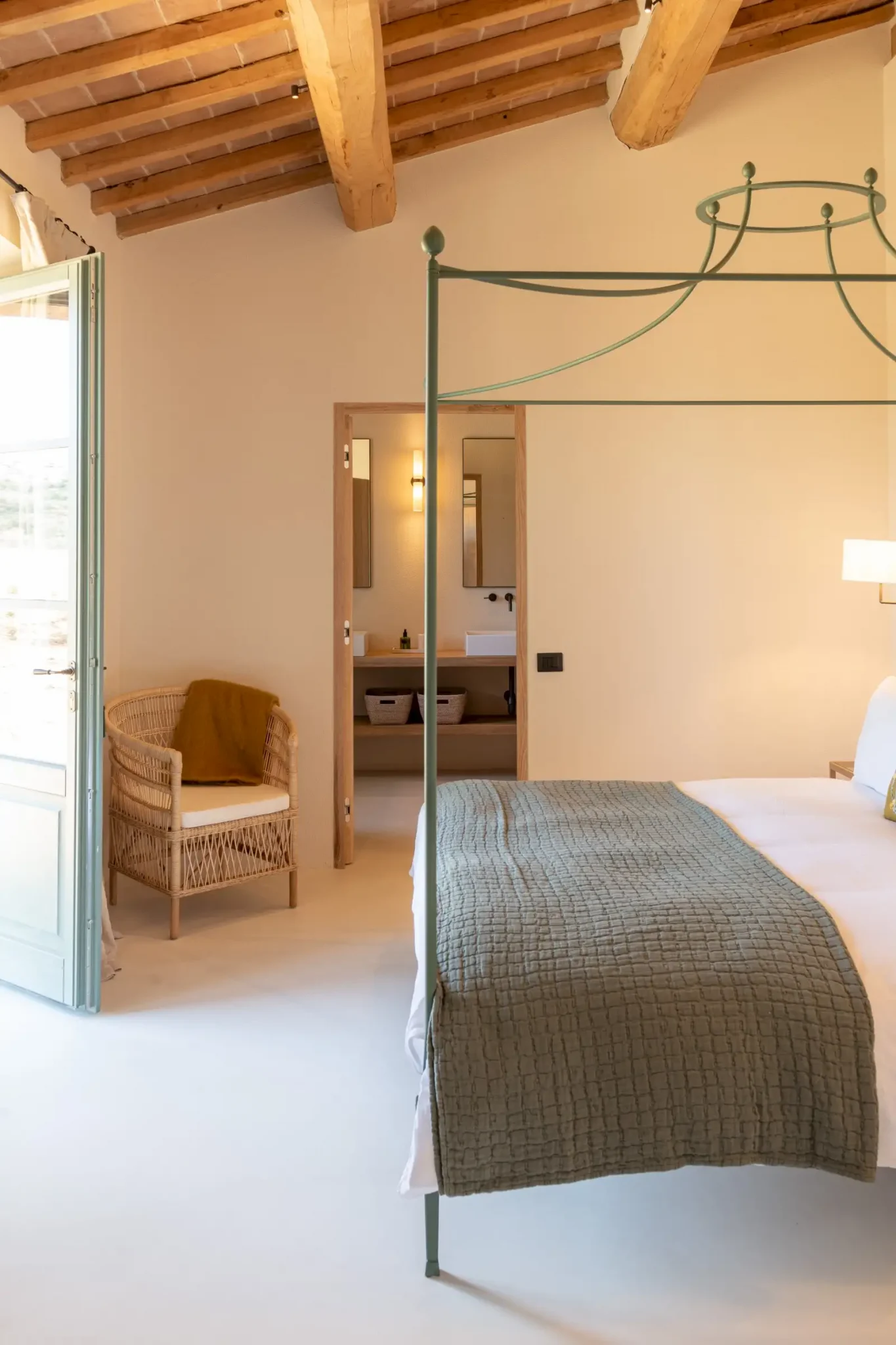chambre avec lit baldaquin métal vert et poutres maison en pierres ancienne rénovée Podere Sirolo Italie