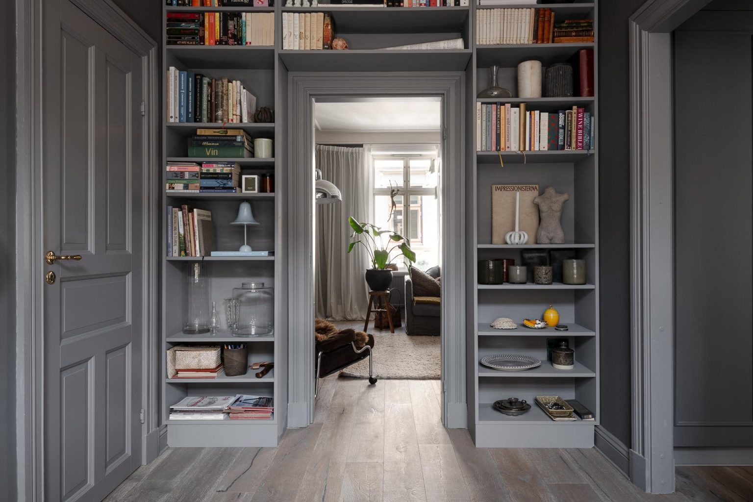 entrée murs gris deux-pièces 66m2 avec bibliothèque autour de la porte