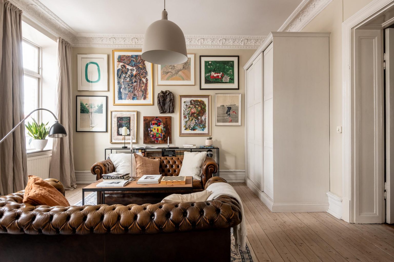 salon avec canapé Chesterfield cuir marron moulures appartement type haussmannien décoration classique chic