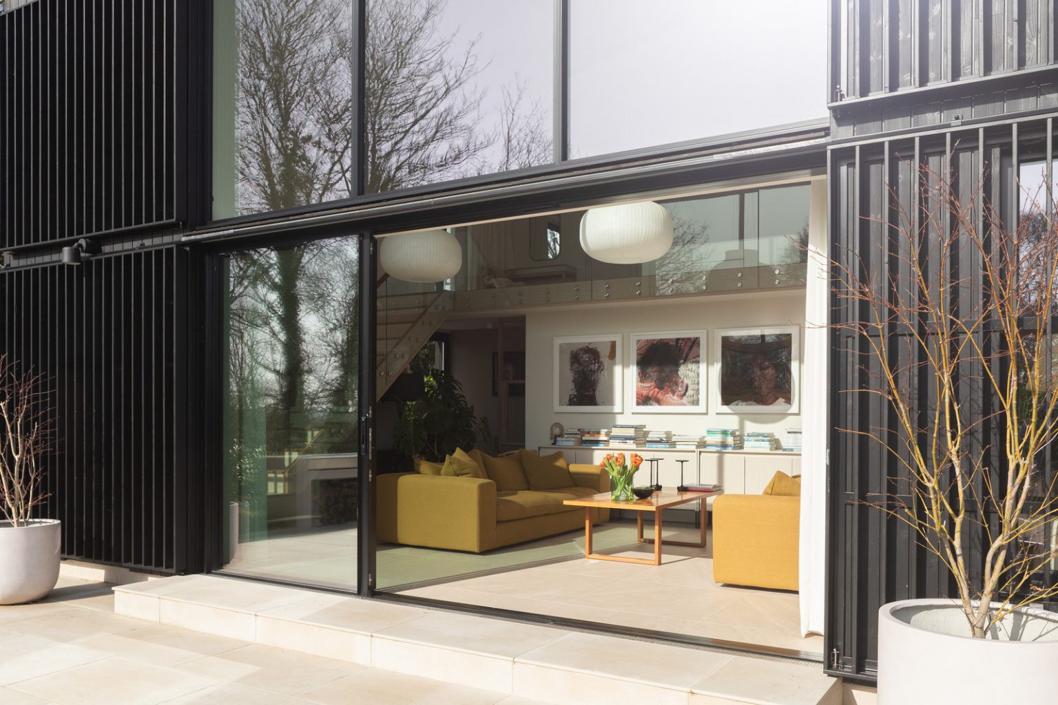 terrasse et salon maison contemporaine durable avec grandes baies vitrées et jardin paysagé