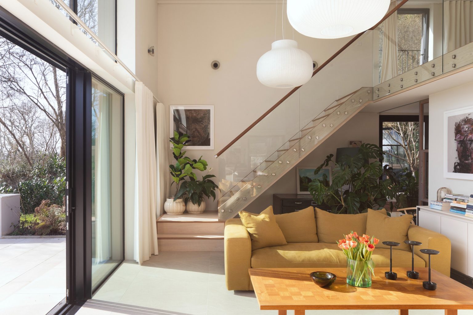 salon double hauteur avec escalier maison contemporaine durable avec grandes baies vitrées et jardin paysagé