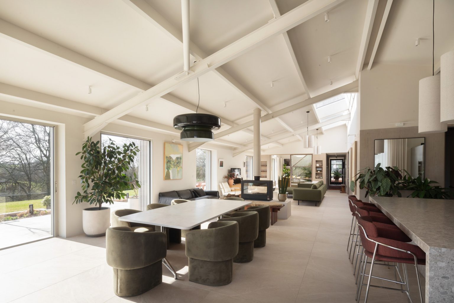 salle à manger et cuisine maison contemporaine durable avec grandes baies vitrées et jardin paysagé