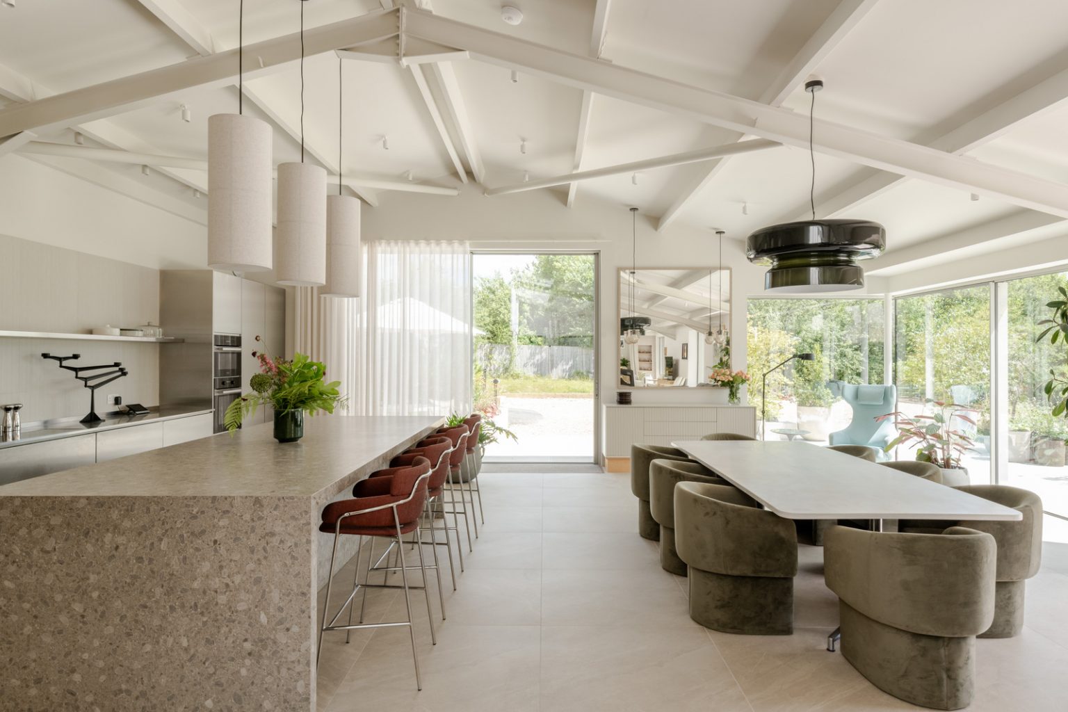 salle à manger et cuisine maison contemporaine durable avec grandes baies vitrées et jardin paysagé