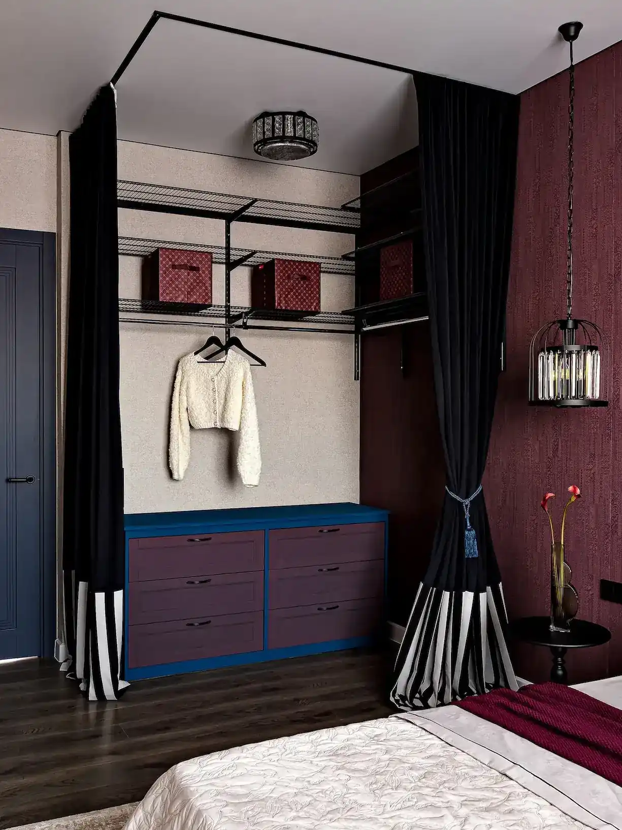 dressing fermé par rideau dans chambre lit bleu mur bordeaux appartement de 45m2 décoration maximaliste et colorée
