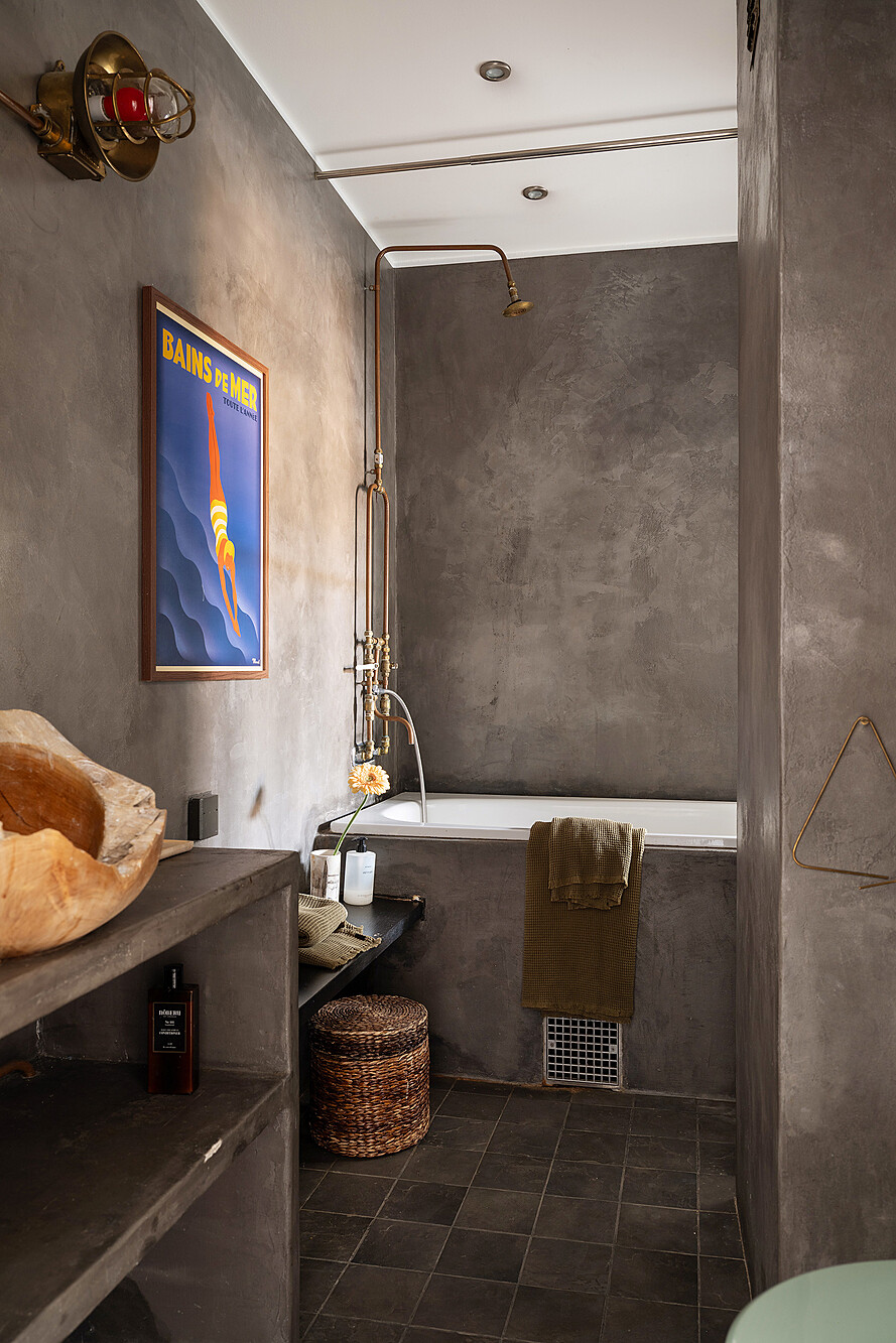salle de bain murs gris béton éclairée en second jour par fenêtre intérieure sur chambre appartement deux-pièces ancien décoration vintage et bohème