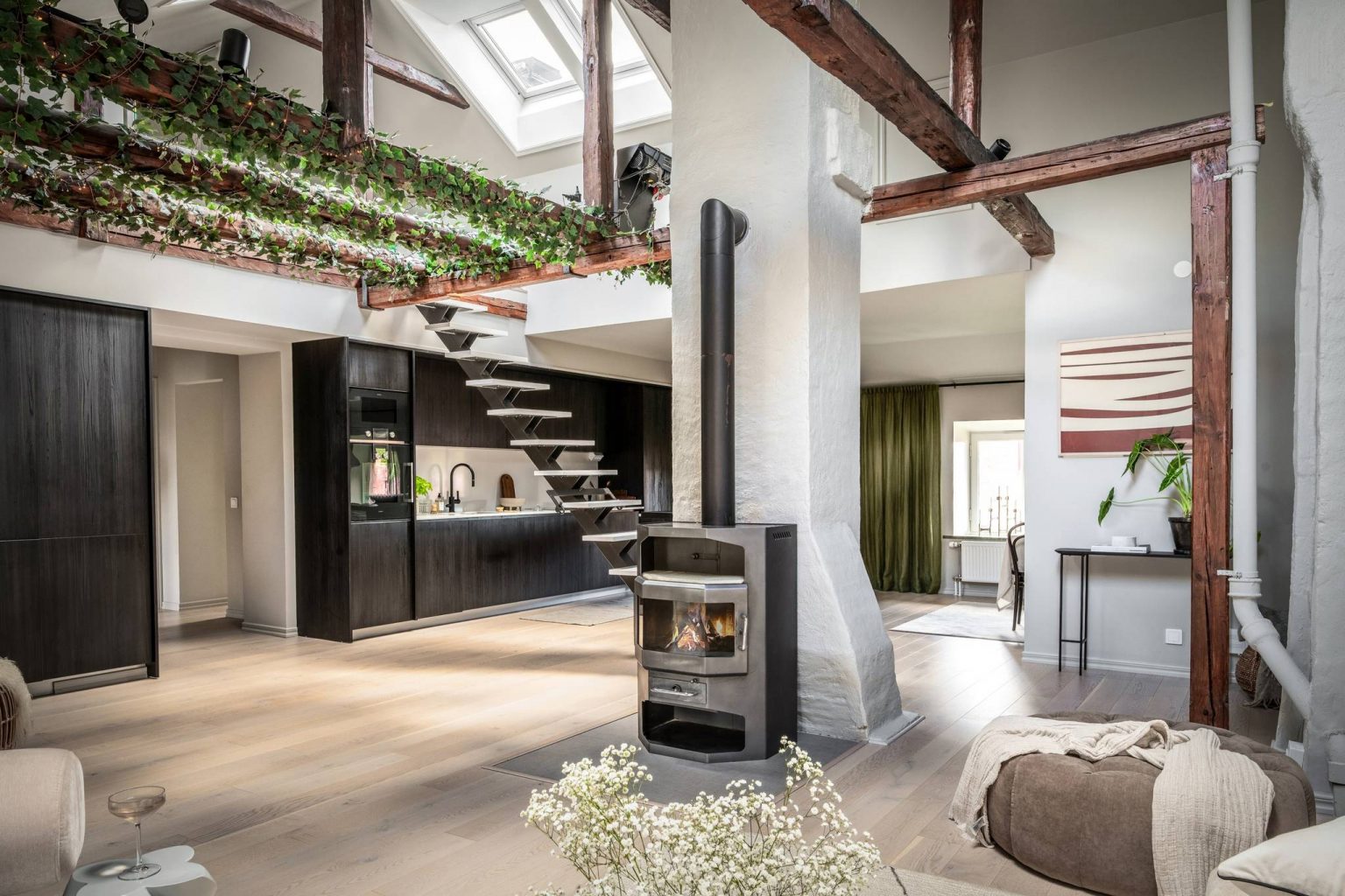 salon double hauteur mansardé avec poêle à bois poutres et plantes vertes décoration scandinave et design
