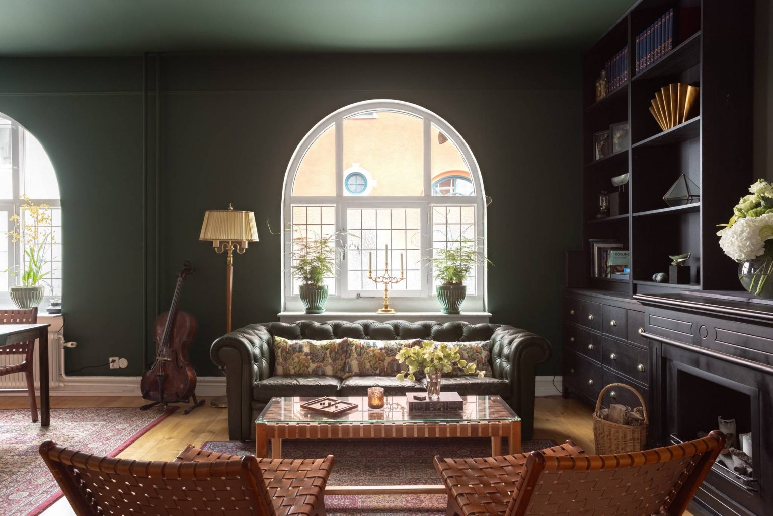 salon avec canapé chesterfield et bibliothèque décoration classique chic duplex 1909 Malmö murs et plafond vert mousse