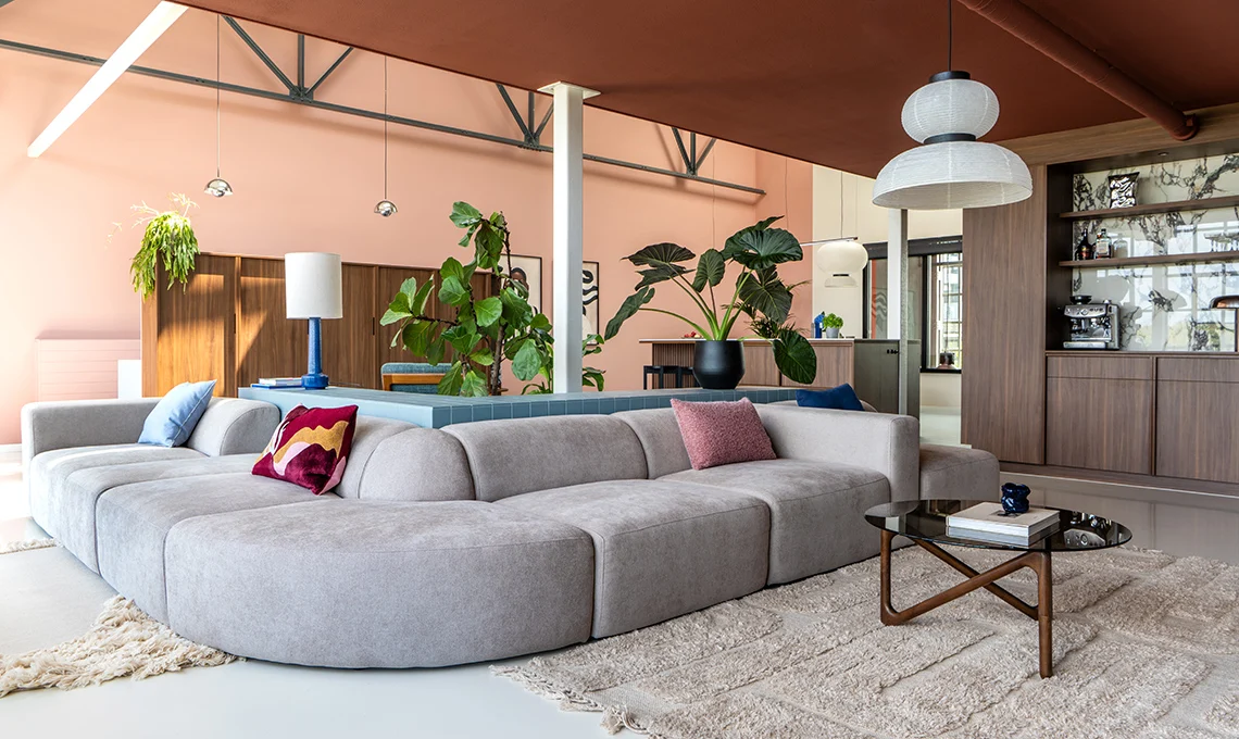 living room with gray sofa and pink wall in a loft in Rotterdam