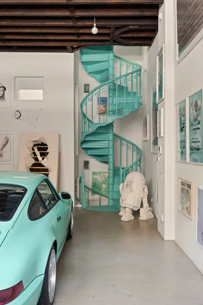 garage avec poutres murs béton et escalier turquoise dans ancienne caserne de pompiers SoHo New York maison de Daniel Arsham