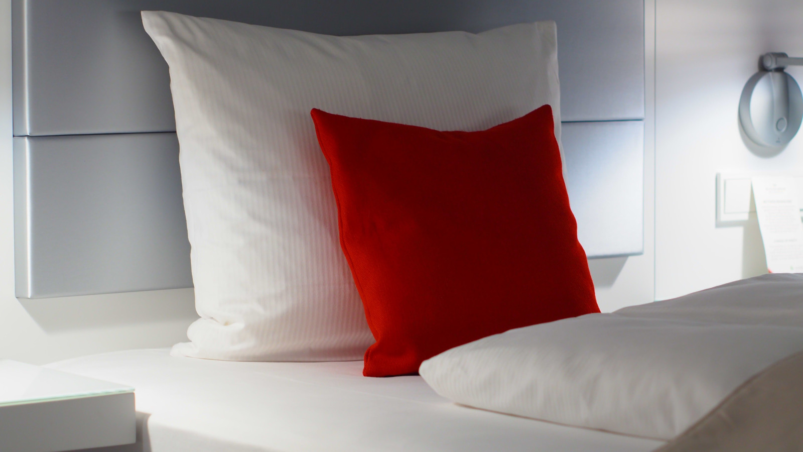 coussin rouge sur lit blanc