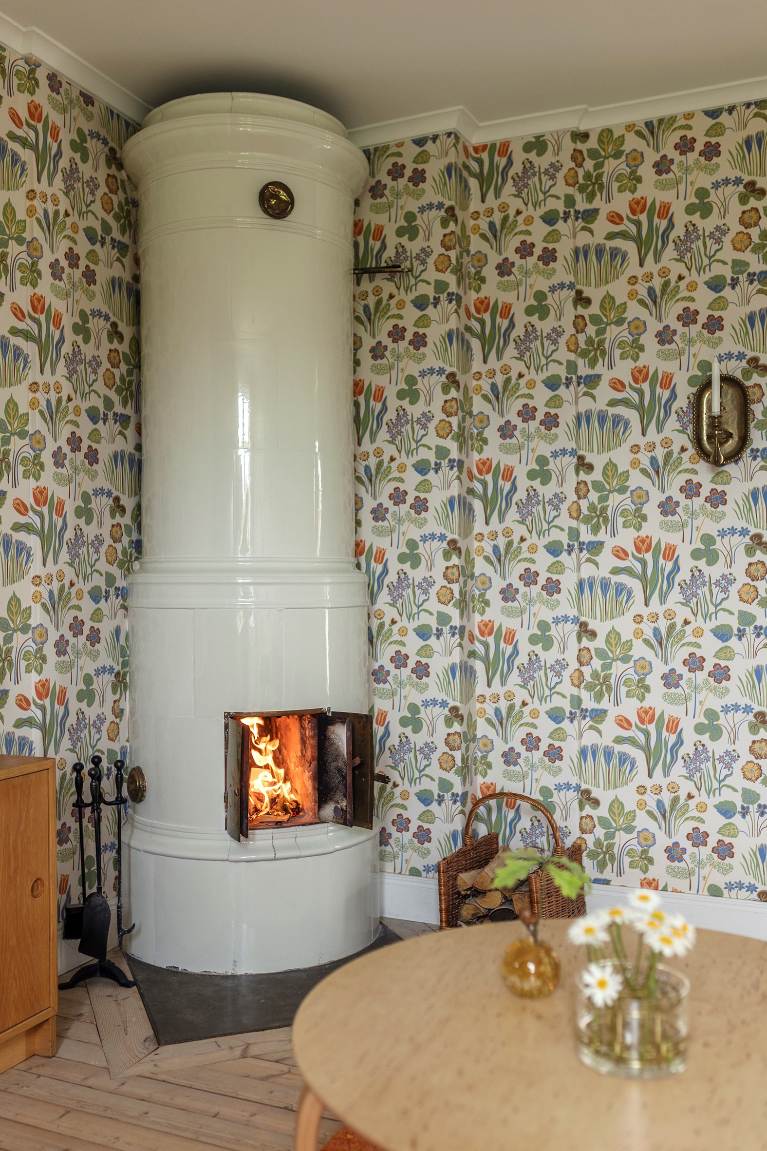 salon papier-peint Joseph Frank avec poêle en faïence décoration vintage et rustique chic maison en bois jaune Suède