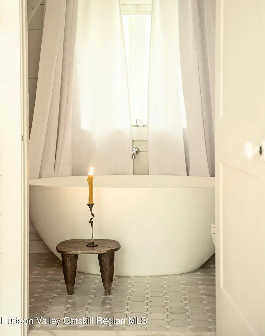 salle de bain baignoire ilot design sol carrelage artisanal beige cabochons blancs décoration naturelle neutre maison A-Frame des années 1970