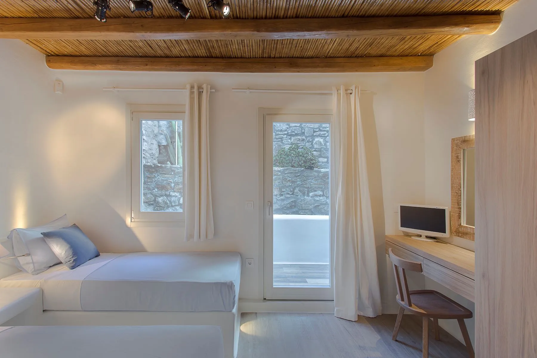 chambre à deux lits décoration contemporaine mur de pierres maison design à Mykonos avec piscine
