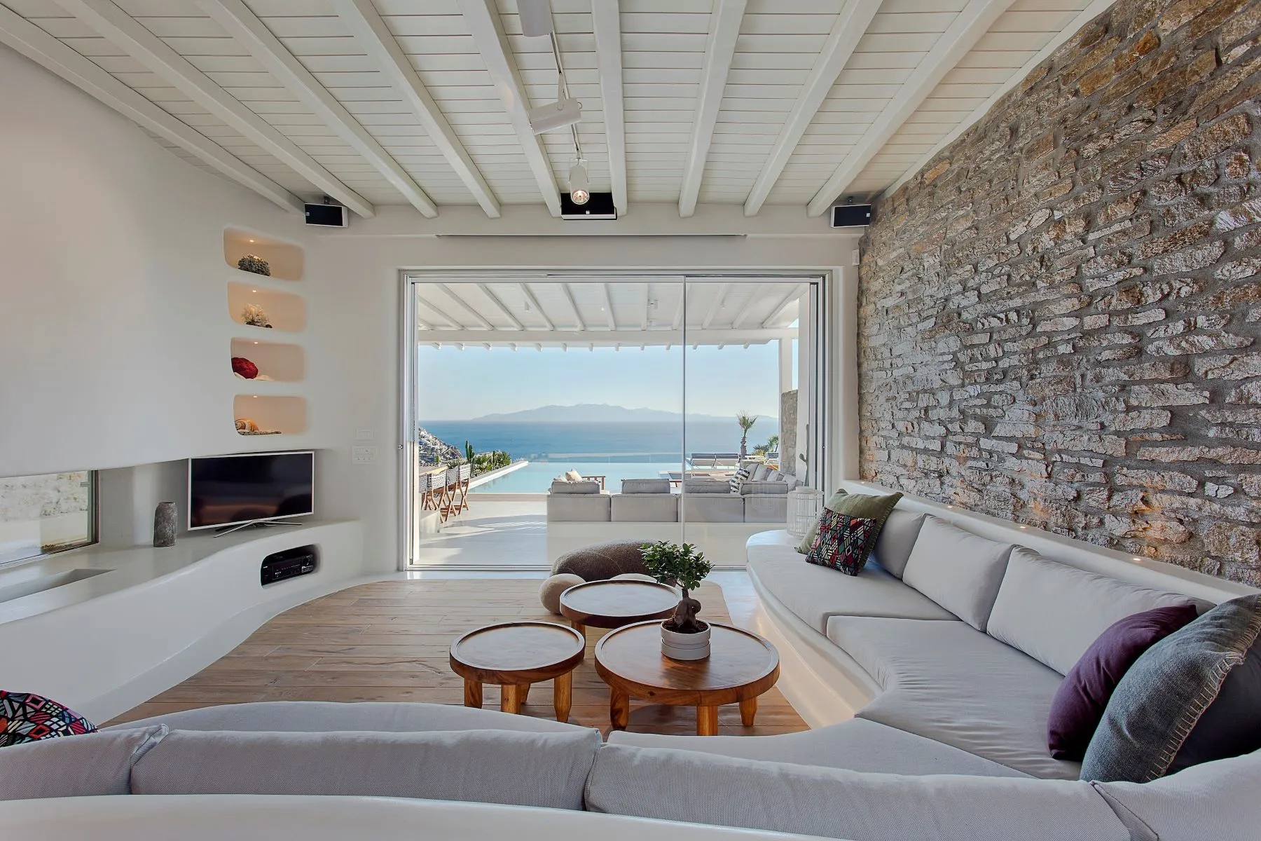 salon vue mer décoration contemporaine mur de pierres et cheminée maison design à Mykonos avec piscine