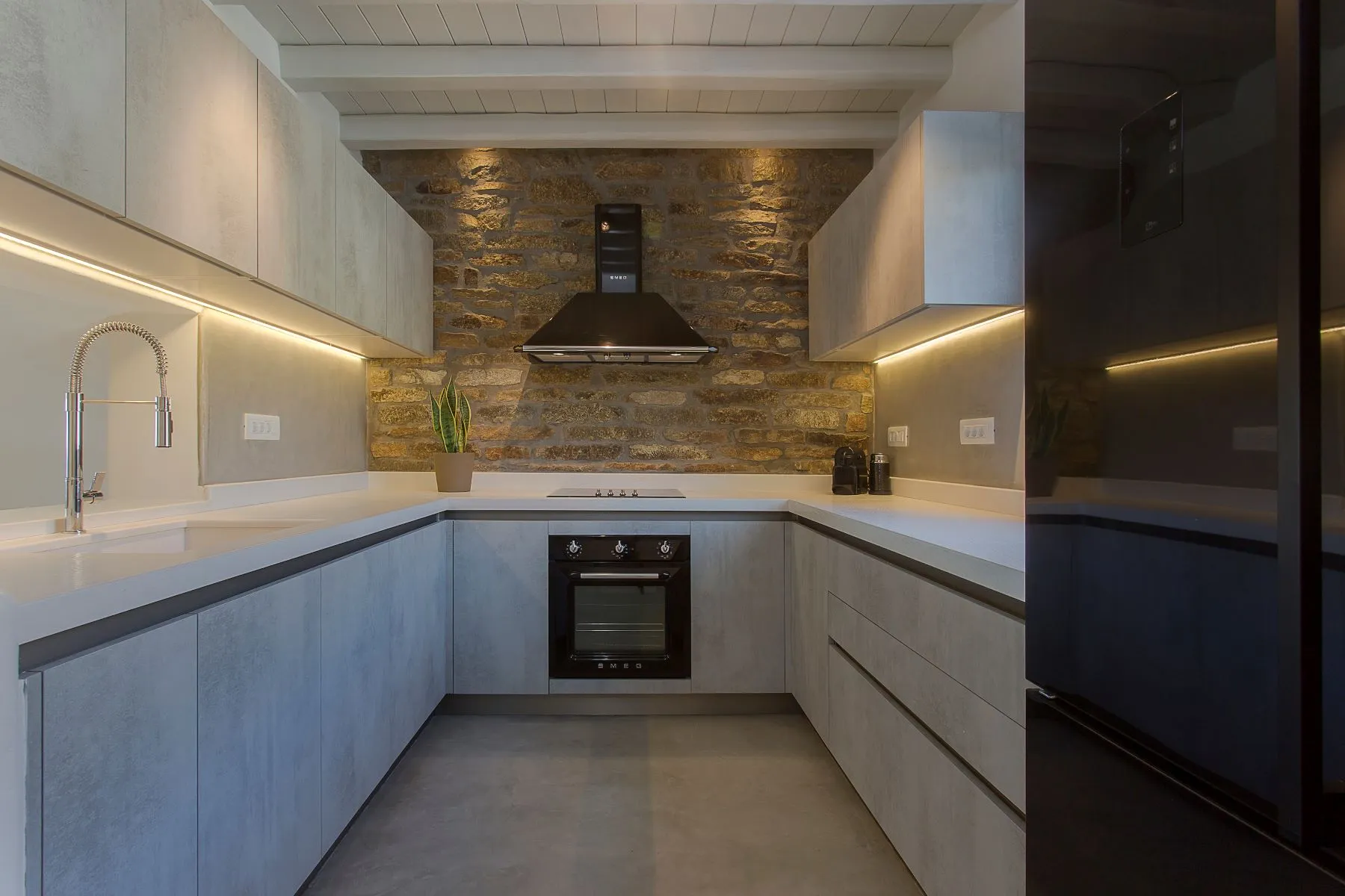 cuisine grise moderne avec mur de pierres et poutres