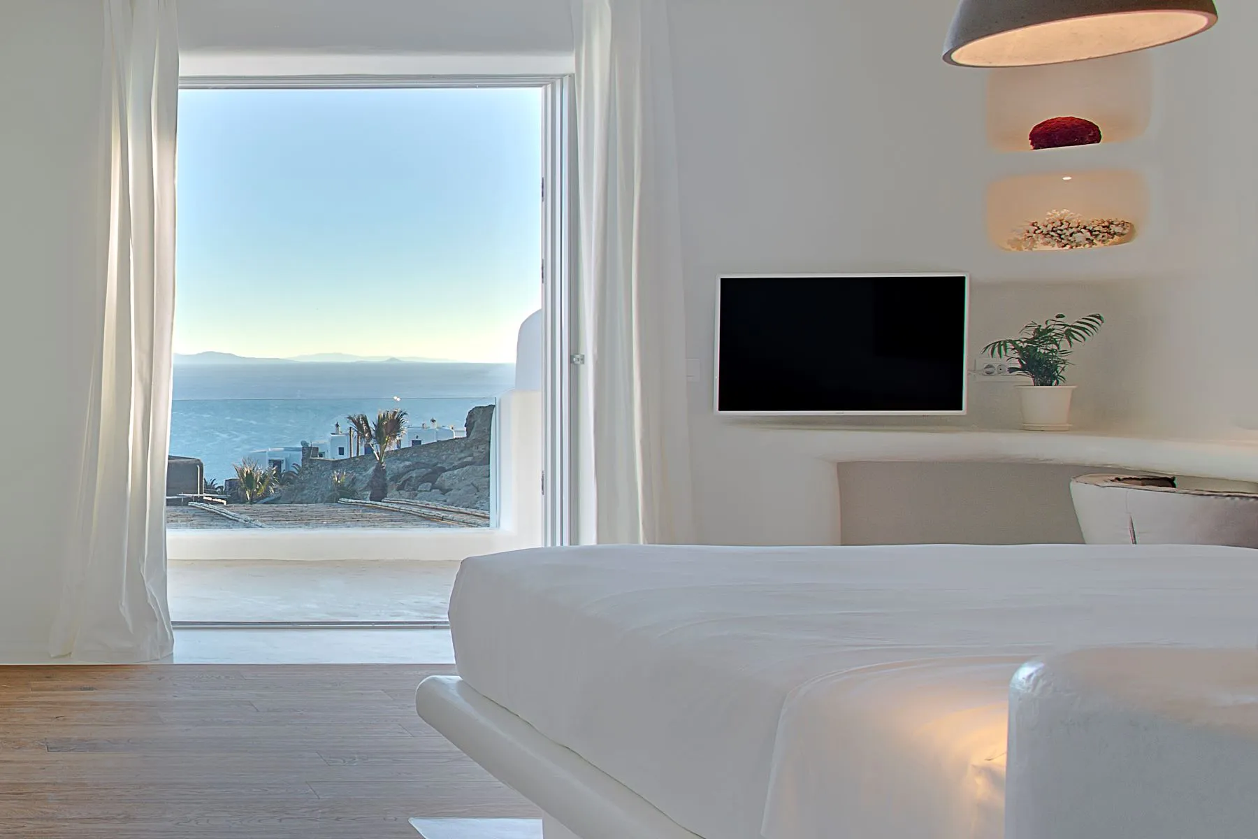 chambre blanche vue mer décoration contemporaine mur de pierres maison design à Mykonos avec piscine