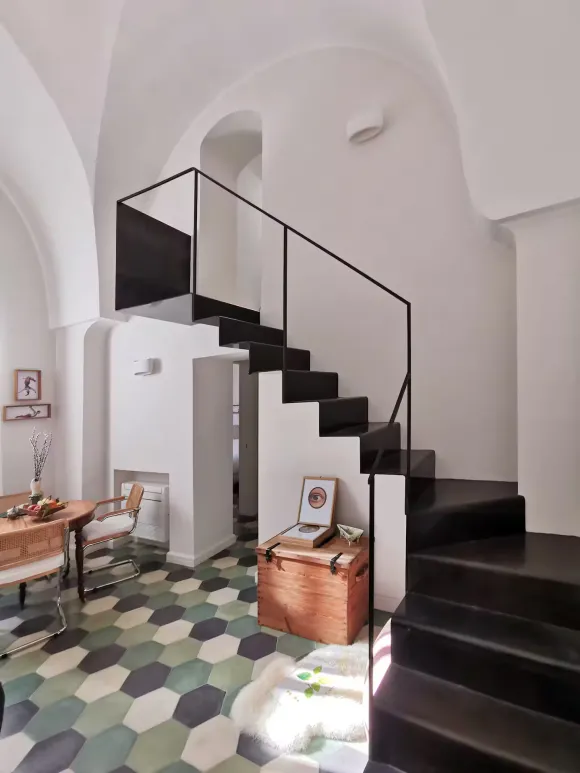 double height living room with stairs green terracotta tiles apartment in Italy in a period palace designer decor