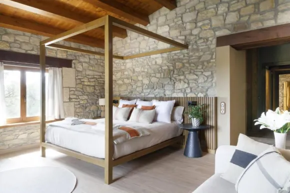 chambre lit baldaquin murs de pierres et poutres décoration contemporaine maison catalane Mas Summit