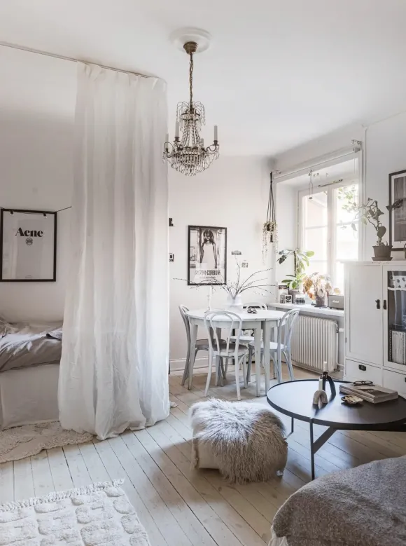 pièce principale avec lit caché par rideaux décoration blanche et scandinave studio 27m2