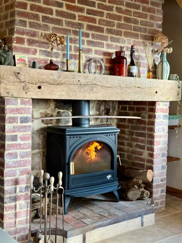 cheminée ancienne en briques avec poêle en fonte noire décoration rustique chic maison ancienne rénovée à colombages en Normandie le Clos du Haut