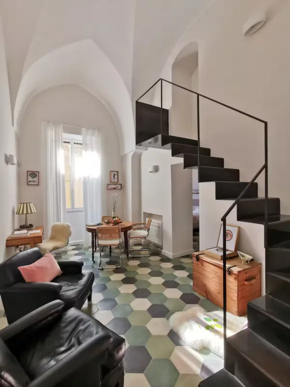 double height living room with stairs green terracotta tiles apartment in Italy in a period palace designer decor