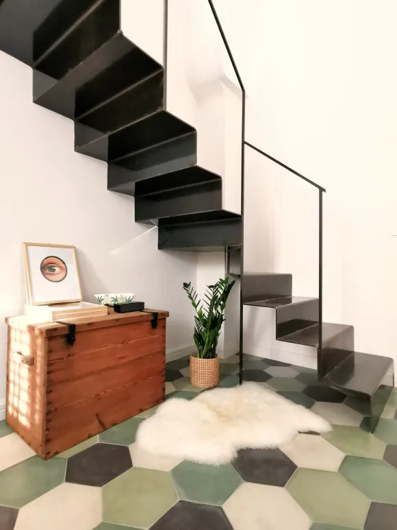 double height living room with stairs green terracotta tiles apartment in Italy in a period palace vintage decor